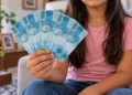 Menina segurando notas de R$ 100, representando a pensão destinada a filhos e dependentes de vítimas de feminicídio.