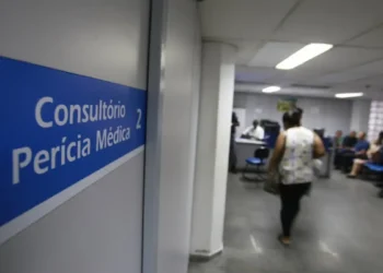 Sala de perícia médica do INSS com placa indicando consultório e atendimento aos segurados.