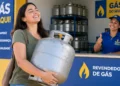 prazo-vale-gas-do-povo-termina-em-9-de-outubro.webp Imagem Mulher segura botijão de gás em frente a revendedora credenciada do programa Gás do Povo