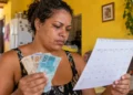 Mulher confere calendário e segura dinheiro, representando as próximas datas de pagamento do Mães de Pernambuco em 2026.