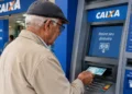 Idoso realiza saque de benefício do INSS em caixa eletrônico da Caixa Econômica Federal, representando a necessidade de retirar o pagamento em até 60 dias para evitar a devolução do valor.