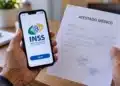 Atestado médico enviado ao INSS pela internet é conferido por inteligência artificial; entenda como 14 Mãos seguram celular com acesso ao INSS e atestado médico