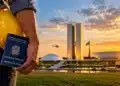 Fim da escala 6x1 vai à promulgação após aprovação no Senado; veja o que muda e quando a regra vale 14 Trabalhador segura capacete e carteira de trabalho diante do Congresso Nacional, em referência ao fim da escala 6x1.
