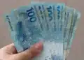 Saque Calamidade do FGTS: veja quais cidades ainda estão habilitadas em outubro e como fazer o pedido 14 Mão segura notas de R$ 100, representando o valor que pode ser retirado pelo Saque Calamidade do FGTS por moradores de cidades que ainda estão habilitadas em outubro.