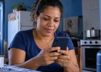 App Meu Social mostra se a família tem vale do Gás do Povo e onde fica a revenda credenciada mais perto 6 Mulher consulta o celular, representando a busca por informações sobre o vale do Gás do Povo pelo app Meu Social.