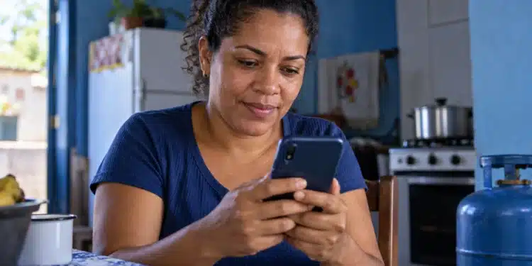 Mulher consulta o celular, representando a busca por informações sobre o vale do Gás do Povo pelo app Meu Social.