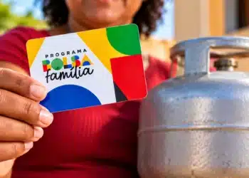 Beneficiária segura cartão do Bolsa Família ao lado de botijão de gás