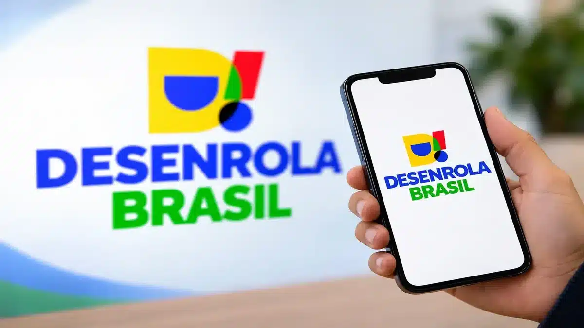 Portaria convoca bancos para a 3ª fase do Desenrola; prazo para enviar dívidas é de cinco dias úteis 2 Mão segurando celular com o logotipo do Desenrola Brasil, ilustrando a inclusão de dívidas de até R$ 10 mil na terceira fase do programa.
