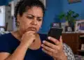 PixMEI ainda não tem repasse: ministro alerta para golpes com cadastros falsos do apoio de até R$ 5 mil 16 Mulher com expressão de preocupação observa a tela do celular em casa, ilustrando o alerta sobre golpes com cadastros falsos do PixMEI.