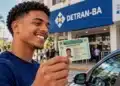 Departamento Estadual de Trânsito da Bahia divulga lista de inscrições deferidas do programa CNH da Gente 17 Jovem segura CNH em frente ao Detran-BA, em imagem relacionada à divulgação das inscrições deferidas do programa CNH da Gente.