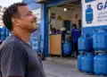 Vale-recarga do Gás do Povo é liberado neste sábado (10) para cerca de 9,3 milhões de famílias 11 Homem em frente a uma distribuidora de gás com botijões azuis, representando as famílias beneficiadas pelo Gás do Povo.