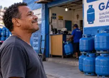 Vale-recarga do Gás do Povo é liberado neste sábado (10) para cerca de 9,3 milhões de famílias 6 Homem em frente a uma distribuidora de gás com botijões azuis, representando as famílias beneficiadas pelo Gás do Povo.