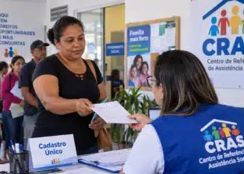Moradores de Serra (ES) podem atualizar o Cadastro Único em mutirão marcado para este sábado (17) 5 Mulher entrega documentos a uma atendente do CRAS durante atendimento do Cadastro Único, com moradores aguardando na fila.