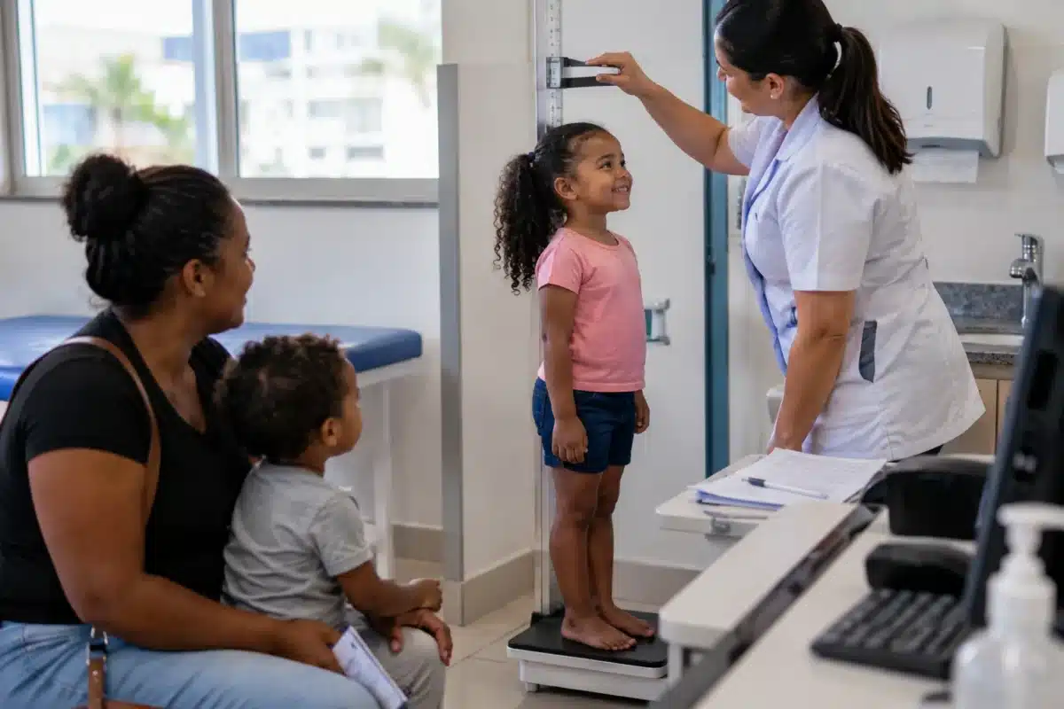 Cartão de pesagem do Bolsa Família: famílias precisam retirar o documento e manter as informações em dia 2 Profissional de saúde mede a altura de uma criança durante acompanhamento em uma unidade de saúde, representando a pesagem obrigatória do Bolsa Família.
