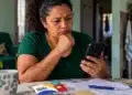 Reajuste do Bolsa Família é automático e não exige recadastramento; veja como se proteger de golpes 14 Beneficiária observa celular ao lado do cartão do Bolsa Família durante alerta sobre golpes no reajuste