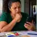 Reajuste do Bolsa Família é automático e não exige recadastramento; veja como se proteger de golpes 14 Beneficiária observa celular ao lado do cartão do Bolsa Família durante alerta sobre golpes no reajuste