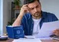Recurso administrativo do Abono Salarial: veja em quais casos o trabalhador pode contestar e onde pedir 14 Trabalhador com expressão de preocupação analisa documentos ao lado da carteira de trabalho, representando dúvidas sobre o recurso administrativo do Abono Salarial.