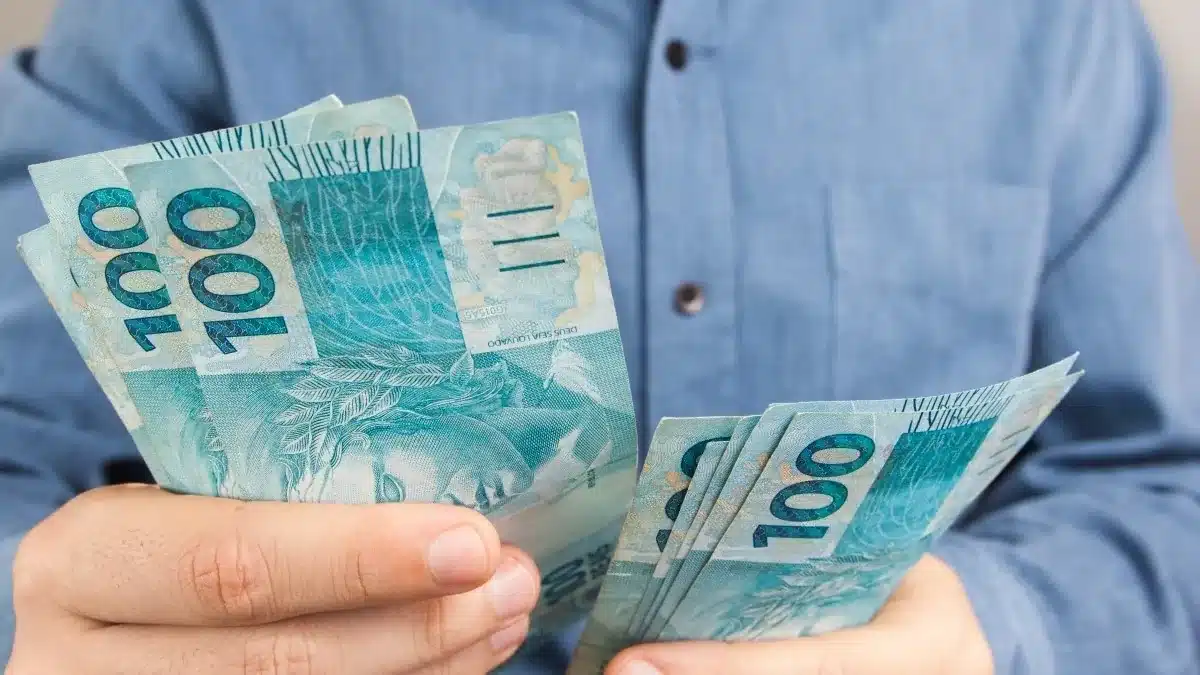 Antecipação do saque-aniversário cai para três parcelas em 1º de novembro; regra atual vale até dia 31 2 Trabalhador segurando cédulas de real para representar o saque-aniversário do FGTS