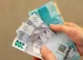 Saque Calamidade do FGTS chega a novas cidades nesta quinta, 8/10; veja como solicitar 14 Mãos seguram cédulas de reais, ilustrando a liberação do Saque Calamidade do FGTS para trabalhadores de novos municípios em 8 de outubro.