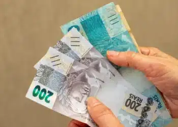 Saque Calamidade do FGTS chega a novas cidades nesta quinta, 8/10; veja como solicitar 5 Mãos seguram cédulas de reais, ilustrando a liberação do Saque Calamidade do FGTS para trabalhadores de novos municípios em 8 de outubro.