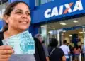 Caixa amplia Saque Calamidade do FGTS para novas cidades nesta terça (27); valor chega a R$ 6.220 14 Mulher segura notas de R$ 100 em frente a uma agência da Caixa, em referência ao Saque Calamidade do FGTS.