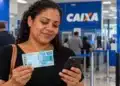 Ressarcimento do PIS/Pasep: veja como solicitar até 31 de outubro para receber o pagamento em novembro 2 Mulher consulta o celular em agência da Caixa enquanto segura uma cédula de R$ 100, representando a solicitação do ressarcimento do PIS/Pasep.