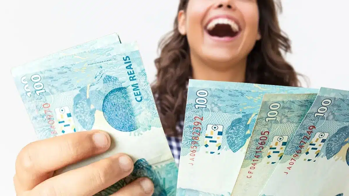 Reajuste do Bolsa Família é automático e não exige recadastramento; veja como se proteger de golpes 2 Mulher segura cédulas de real representando os novos valores do Bolsa Família após o reajuste de outubro de 2026